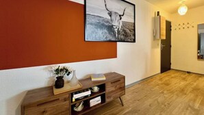 Un corridoio con un tavolino consolle in legno, un quadro con l'immagine di un toro e una porta che dà su un'altra stanza.