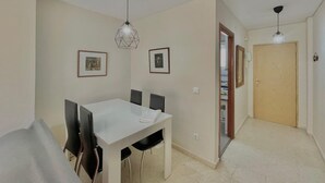 A dining area with a white table and chairs, two pendant lights, and framed pictures on the wall. - TERRASOL CAPRI 2 (Torre del Mar)