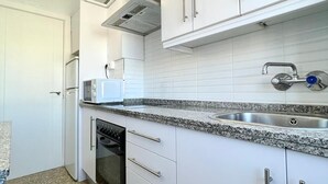 A kitchen with white cabinets, a granite countertop, a stainless steel sink, and a dishwasher.