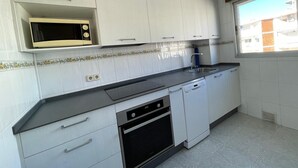 Una cocina con armarios blancos, microondas, fregadero y lavavajillas.