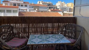 A balcony with wicker furniture and a patterned table, overlooking a cityscape with terracotta-roofed buildings. - TERRASOL PLAZAMAR 6-2 (Torre del Mar)