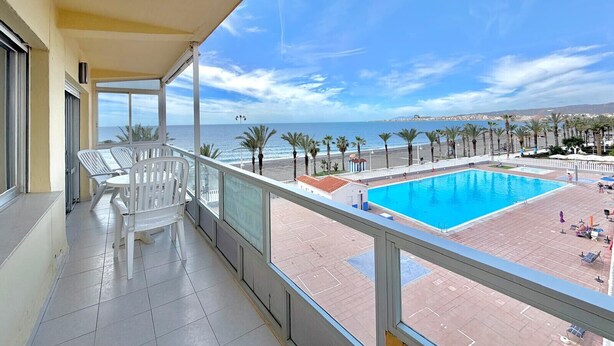 Ein Balkon mit Blick auf ein Schwimmbecken und den Strand.