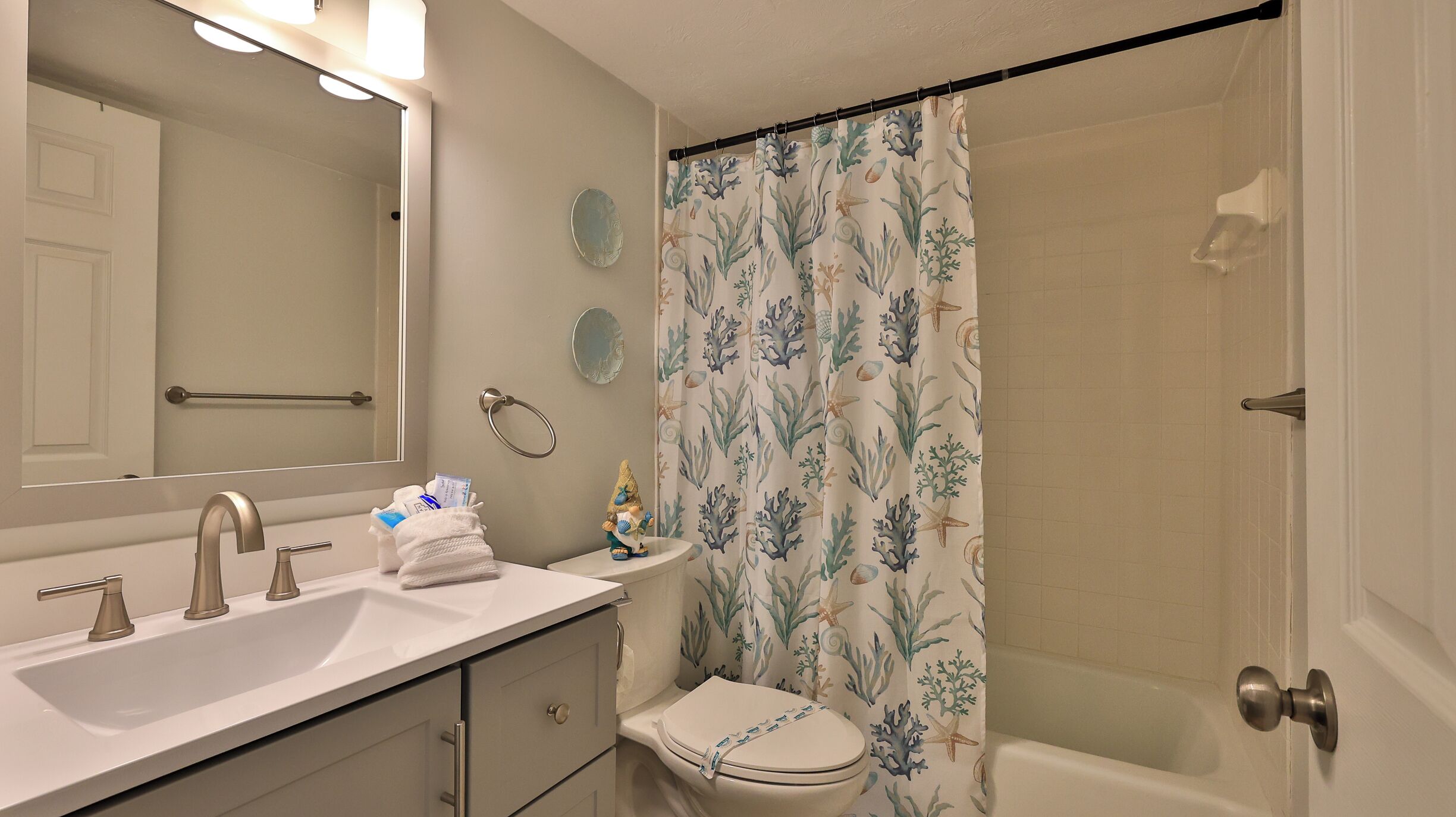 Un baño con lavabo, espejo, inodoro y cortina de ducha.