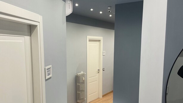 A hallway with wooden flooring, recessed ceiling lights, and white doors.