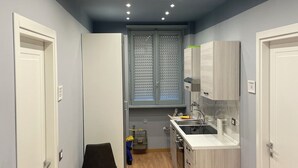 A compact kitchen with a central island, a window with blinds, and a built-in oven.