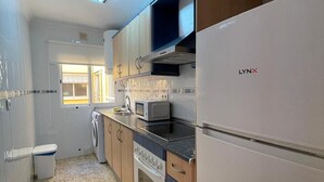 Cocina compacta con microondas integrado, estufa de acero inoxidable y refrigerador blanco.