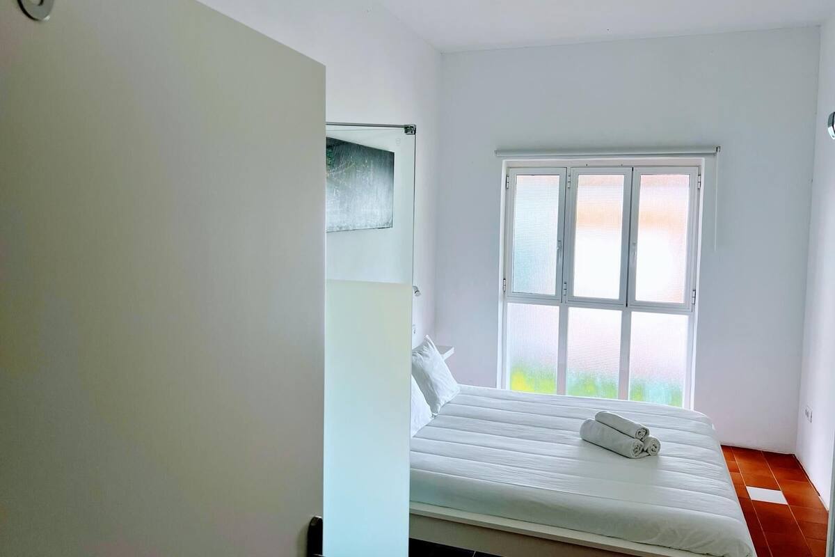 Un dormitorio con una cama, una ventana y una puerta.