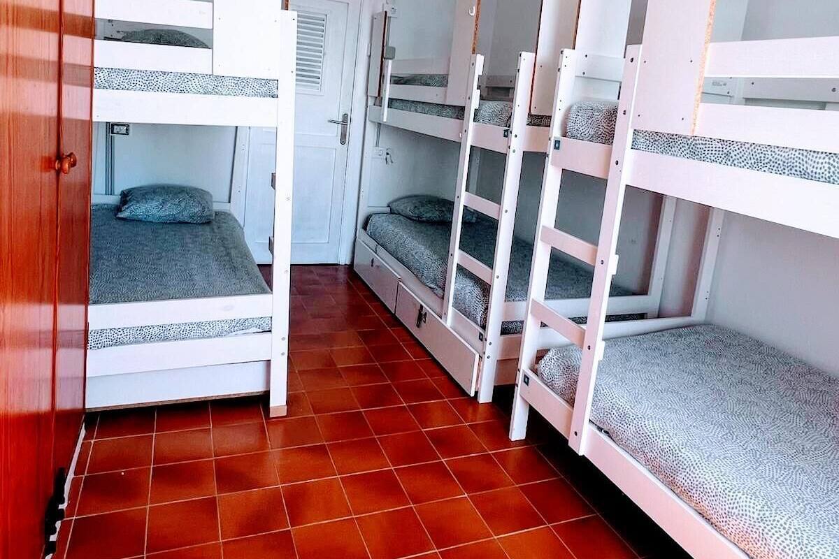 Un dormitorio con literas, un armario de madera y suelo de baldosas.