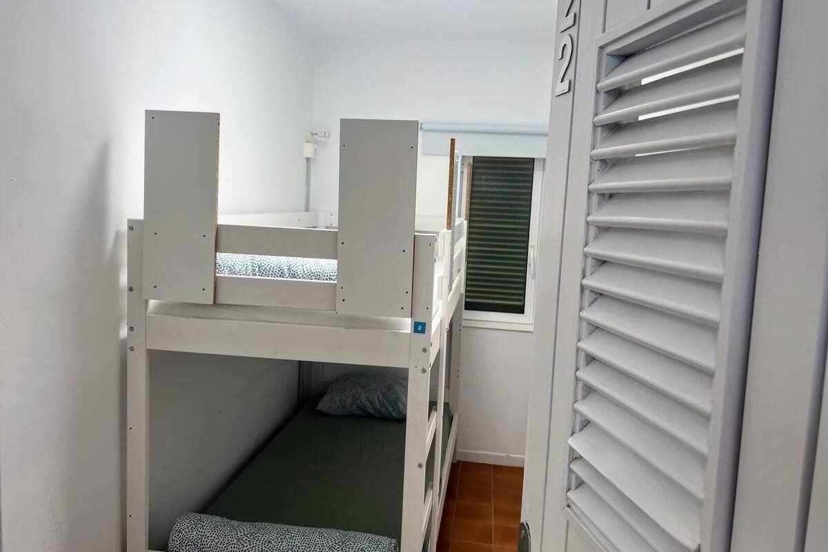 Habitación con literas, ventana y radiador.