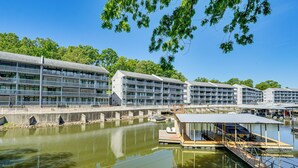 A waterfront hotel with multiple balconies, a dock, and a reflection in the water. - Private Dock + Lake View: Spacious Ozarks Retreat (Osage Beach)
