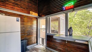 A kitchen with wooden walls, a refrigerator, a trash can, and a window with a view of trees. - Private Dock + Lake View: Spacious Ozarks Retreat (Osage Beach)