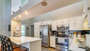 A modern kitchen with white cabinetry, stainless steel appliances, and a central island. - Private Dock + Lake View: Spacious Ozarks Retreat (Osage Beach)