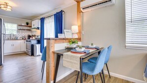 Una cucina moderna con travi in legno, un'area pranzo con sedie blu e un condizionatore d'aria a parete.