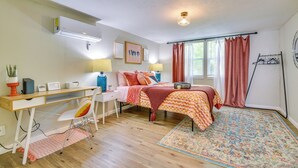 Una camera da letto con una scrivania in legno, un letto con copriletto a quadretti, un tappeto decorato e una finestra con tende.