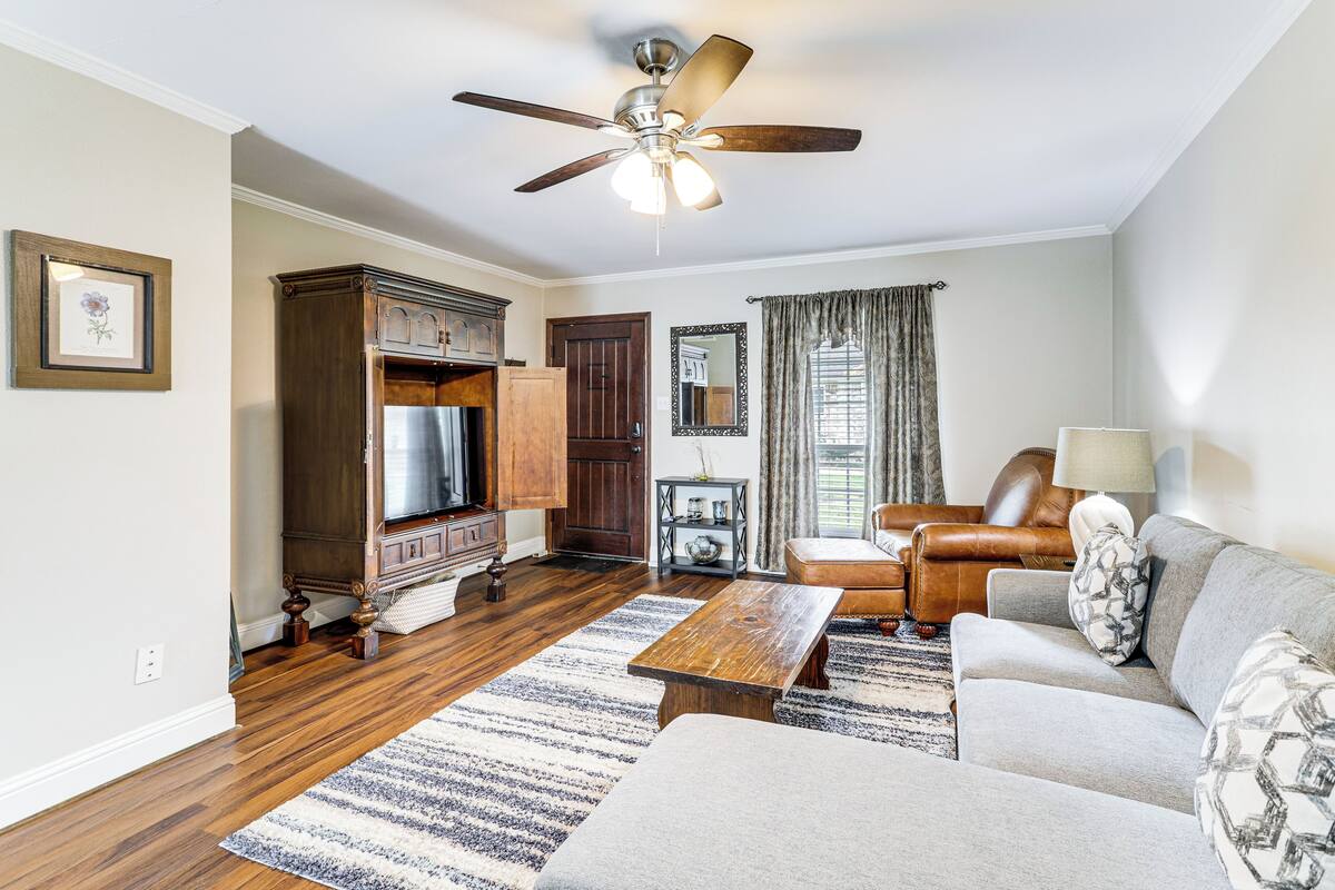 A living room with hardwood floors, a ceiling fan, a sofa, a coffee table, and a TV.