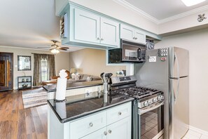 Una cocina moderna con armarios azul claro, estufa a gas, microondas y refrigerador.