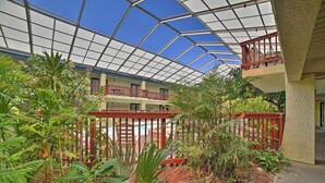 A covered outdoor area with a pool, surrounded by various plants and a wooden fence. - Walk to Padre Beach: Studio w/ Hot Tub Access (Corpus Christi)