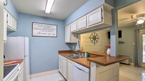 A compact kitchen with white cabinets, a wooden countertop, and a built-in dishwasher. - Walk to Padre Beach: Studio w/ Hot Tub Access (Corpus Christi)