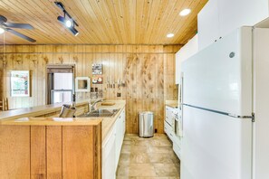 Eine moderne Küche mit Holzvertäfelung, einem Edelstahl-Spülbecken, einem Kühlschrank und einer Mikrowelle.