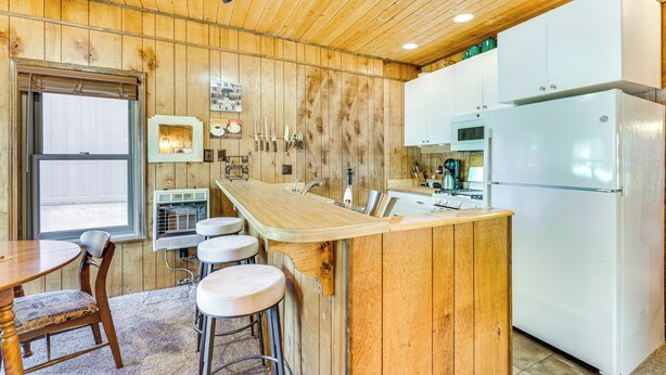 Eine Küche mit Holzwänden, einer zentralen Kochinsel, Barhocker, einem Kühlschrank und einer Mikrowelle.