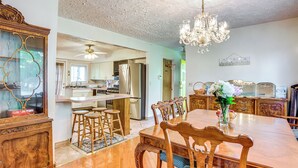 A spacious dining area with a wooden table and chairs, a chandelier, and a view into the kitchen. - Lakefront Group Getaway w/ Dock in Baldwin! (Baldwin)
