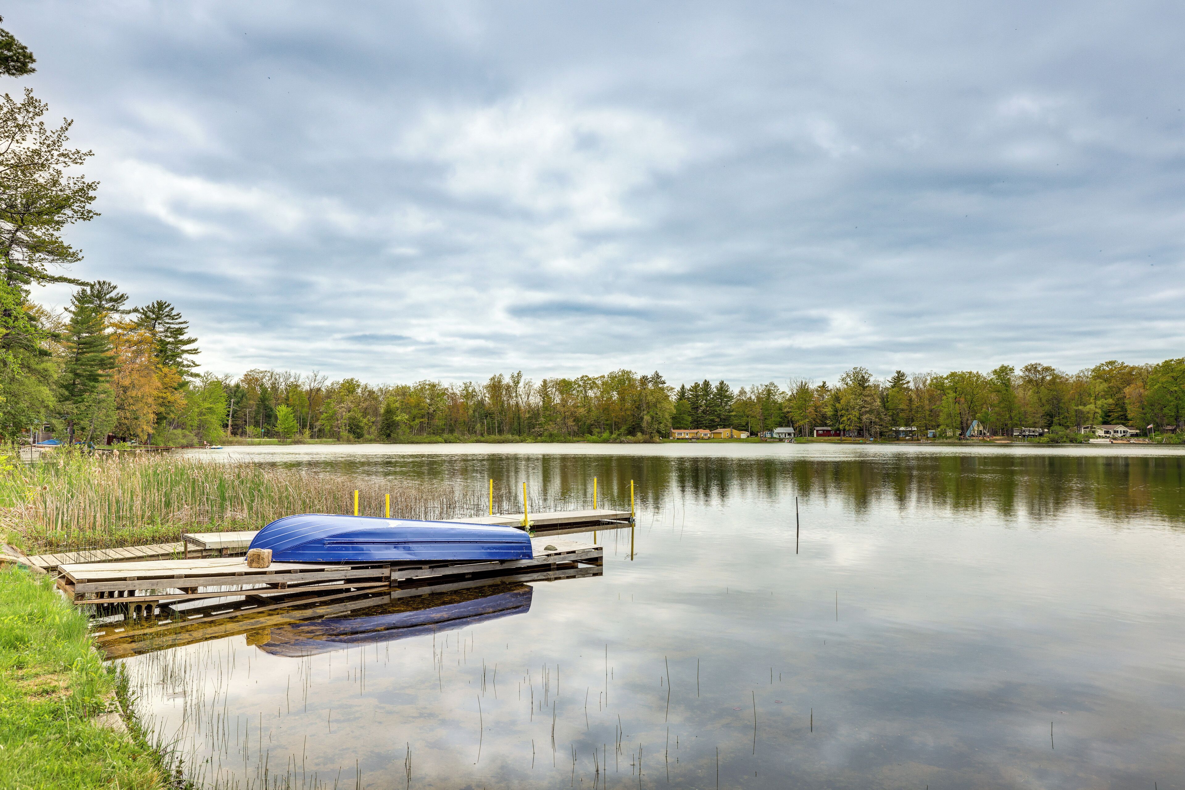 Un lac paisible avec un quai et un bateau bleu.