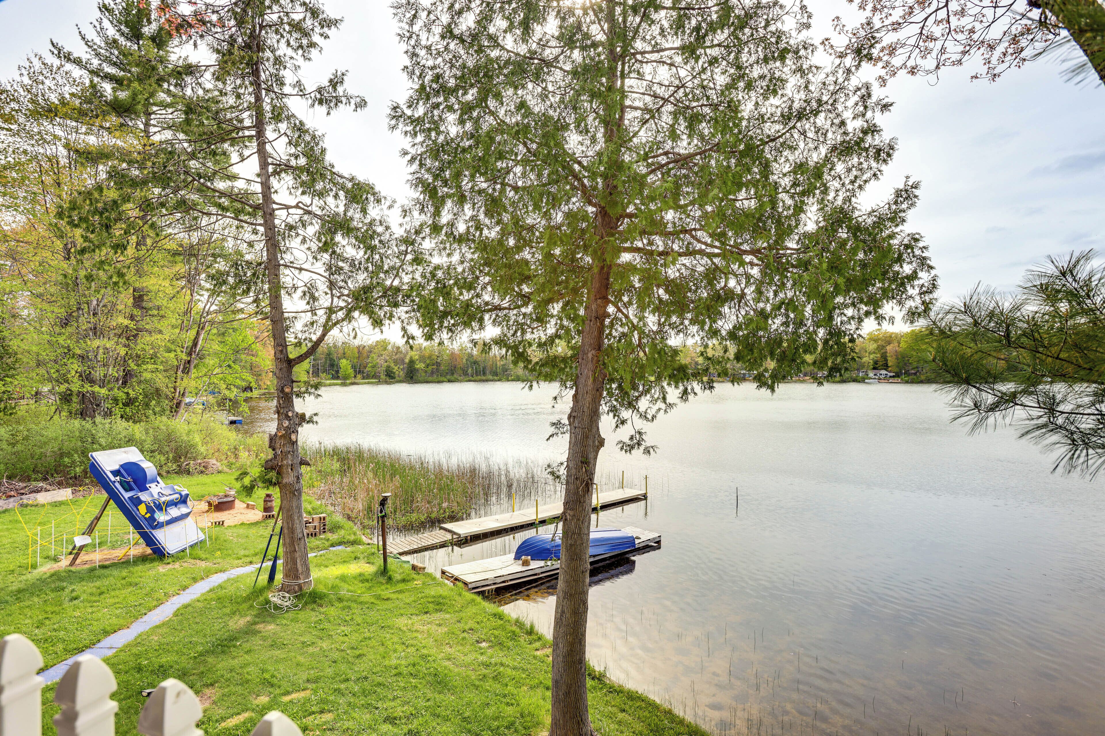 A lakeside property with a dock, a boat, and a grassy area.