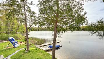 A lakeside property with a dock, a boat, and a grassy area.