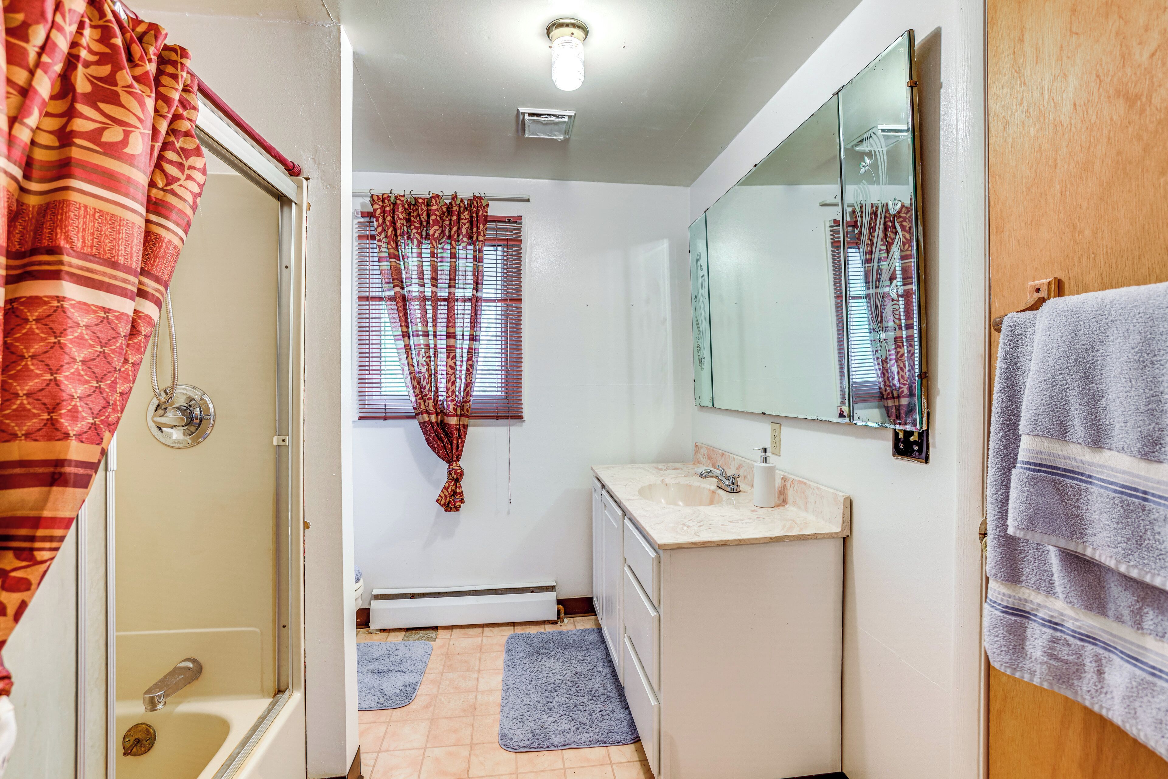 Une salle de bain équipée d’une douche, d’un lavabo, d’un miroir et d’un porte-serviettes.