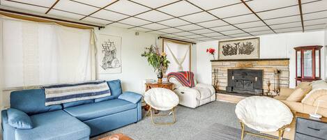 A living room with a blue sofa, a white armchair, a wooden coffee table, and a fireplace.