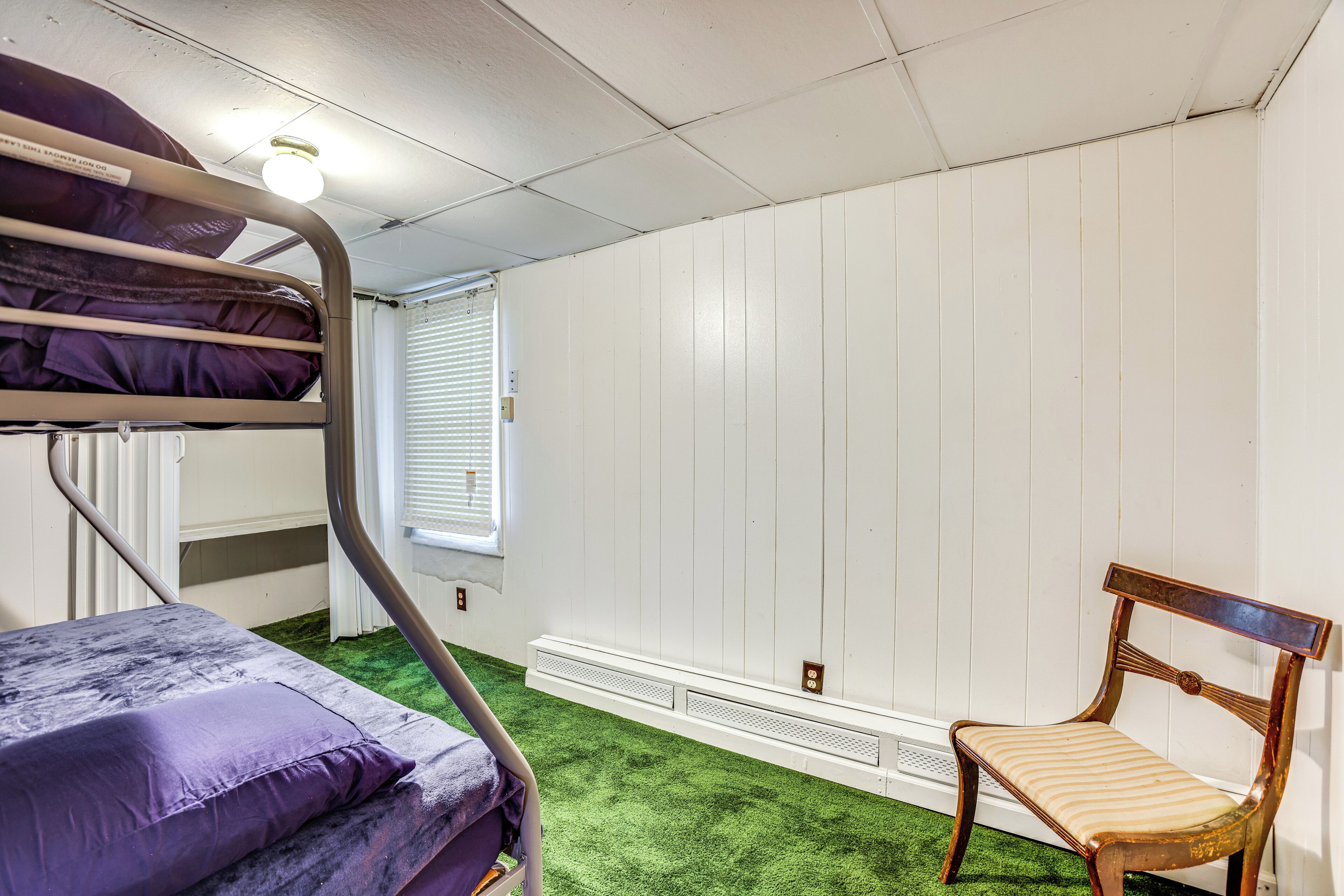 A bunk bed with a purple mattress, a wooden chair, and a radiator.