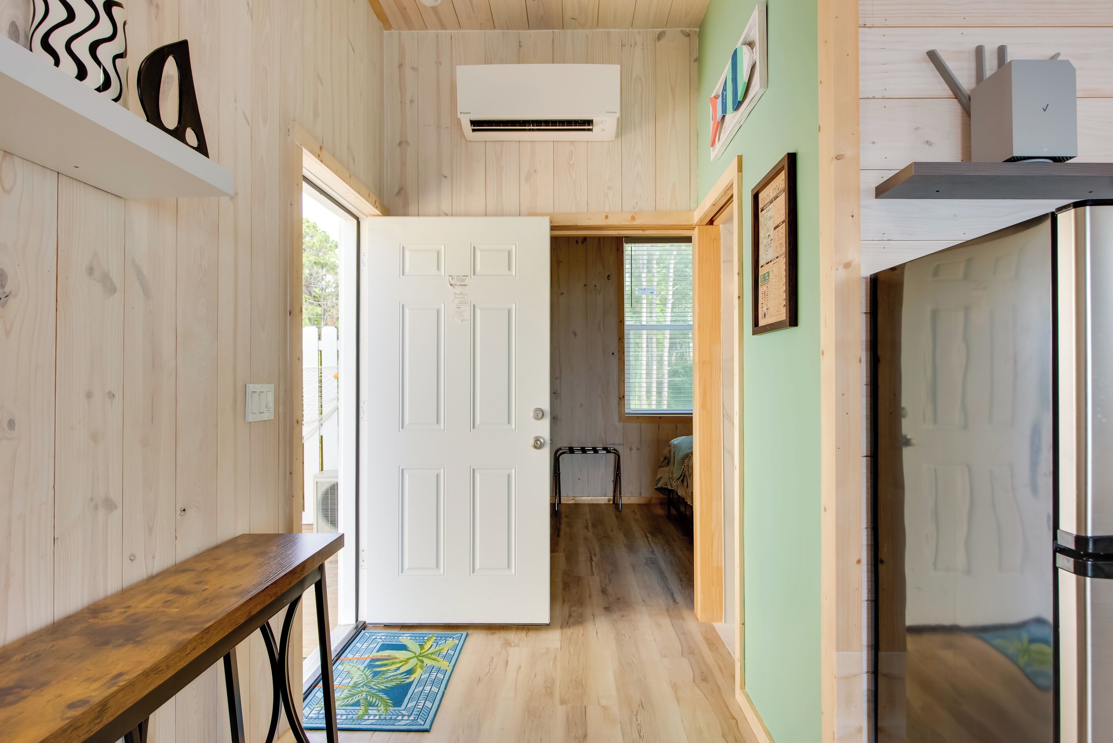 Un intérieur en bois avec une porte blanche, un banc et un petit tapis.