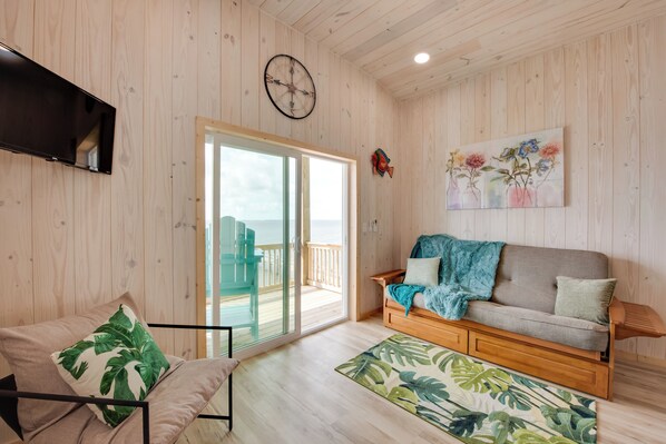 A wooden interior with a sofa, a TV, a clock, and a painting.