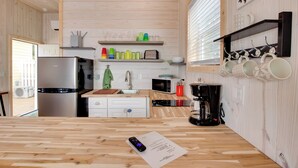 Een moderne keuken met houten kastjes, een roestvrijstalen koelkast, een magnetron en een koffiezetapparaat.