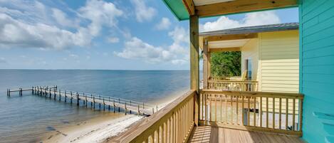 A wooden deck with a view of the beach and ocean.