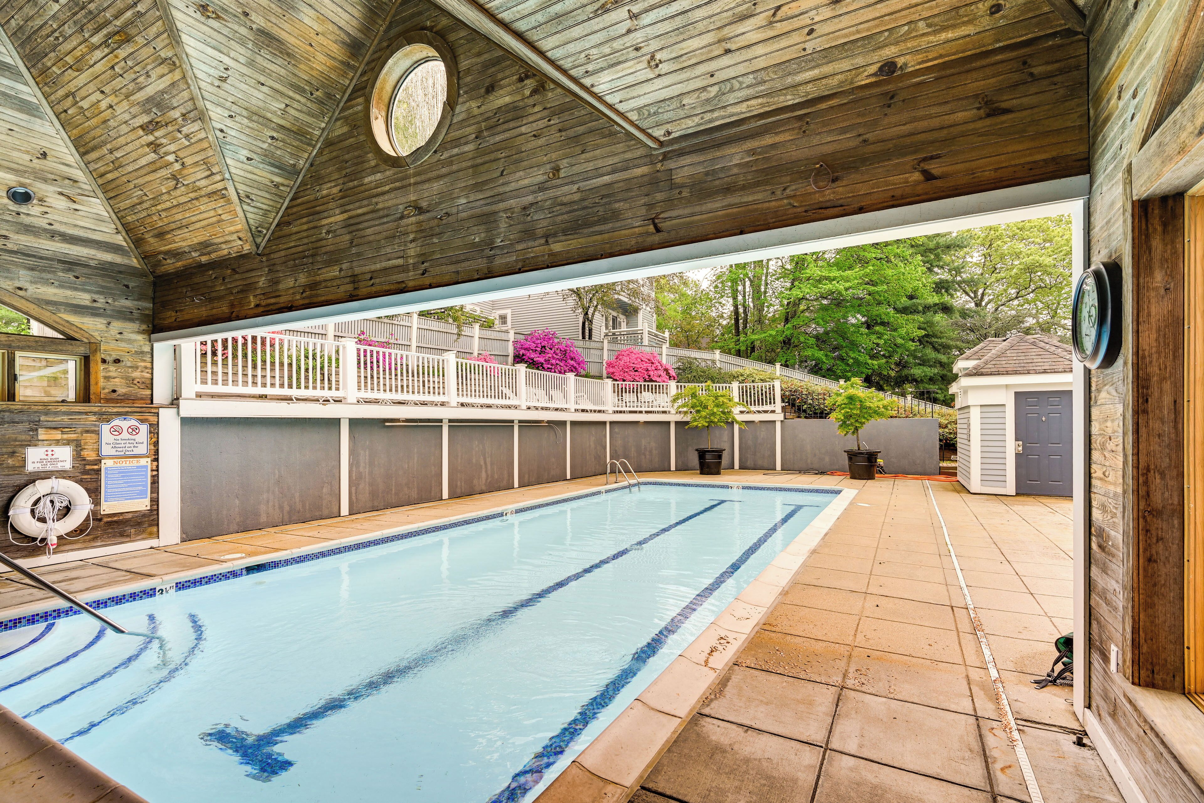A swimming pool with a wooden deck and a covered area.