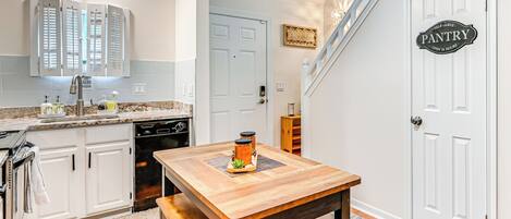 A kitchen with white cabinets, a wooden table, and a sign indicating a pantry.