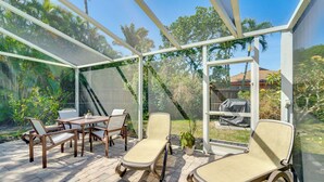 Een overdekt terras met een tafel, stoelen, een lounge stoel en een potplant.