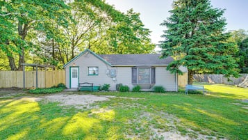 Situated on a quiet lawn, this charming house features a front porch with a bench and a window above the entrance.