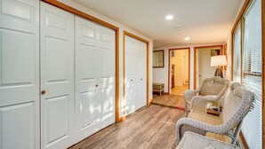 A hallway with white doors, wicker furniture, and a lamp. - Pet-friendly Little Egg Harbor Home w/ Fenced Yard (Tuckerton)