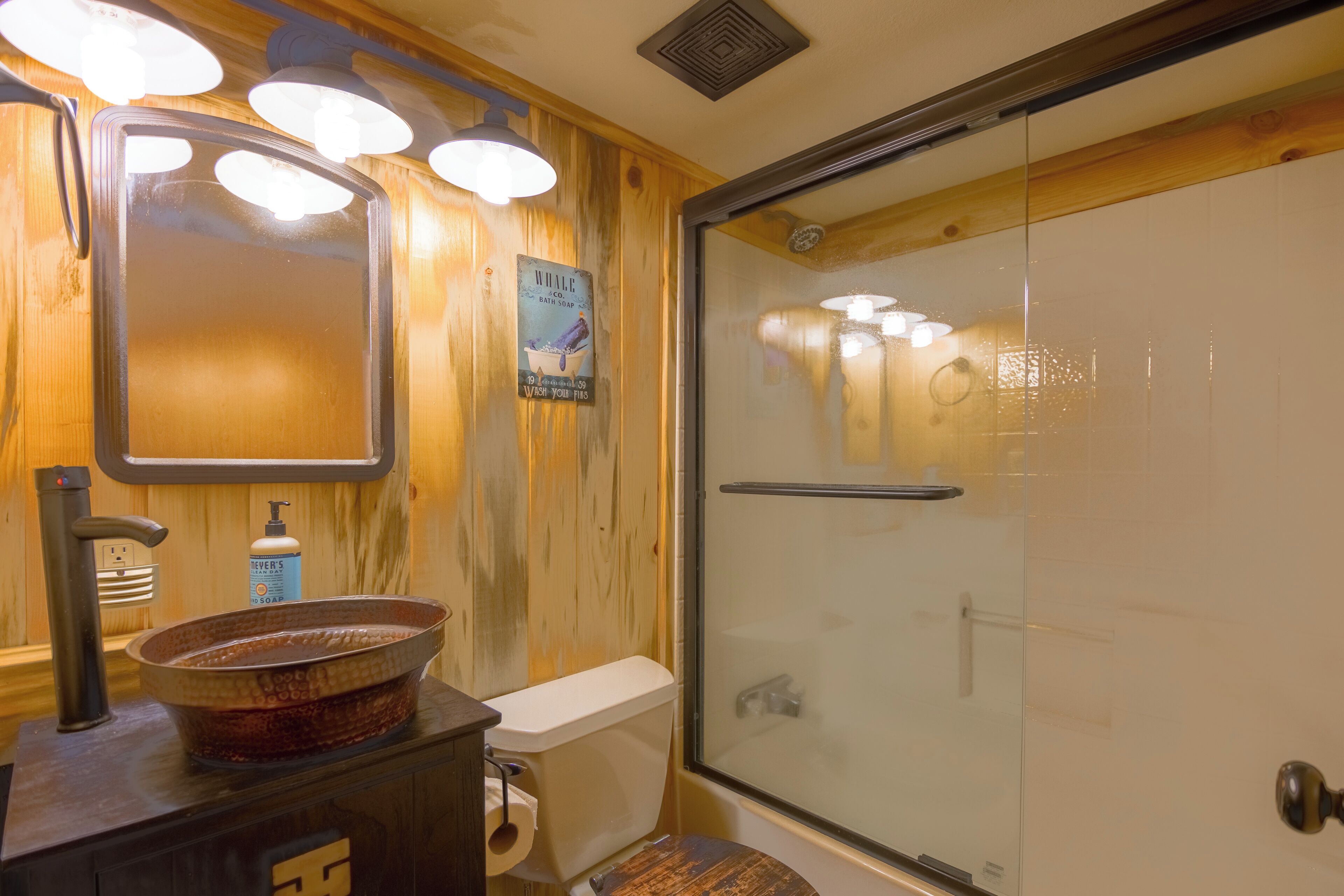 Une salle de bain avec un meuble-lavabo en bois, une cabine de douche en verre et des toilettes.
