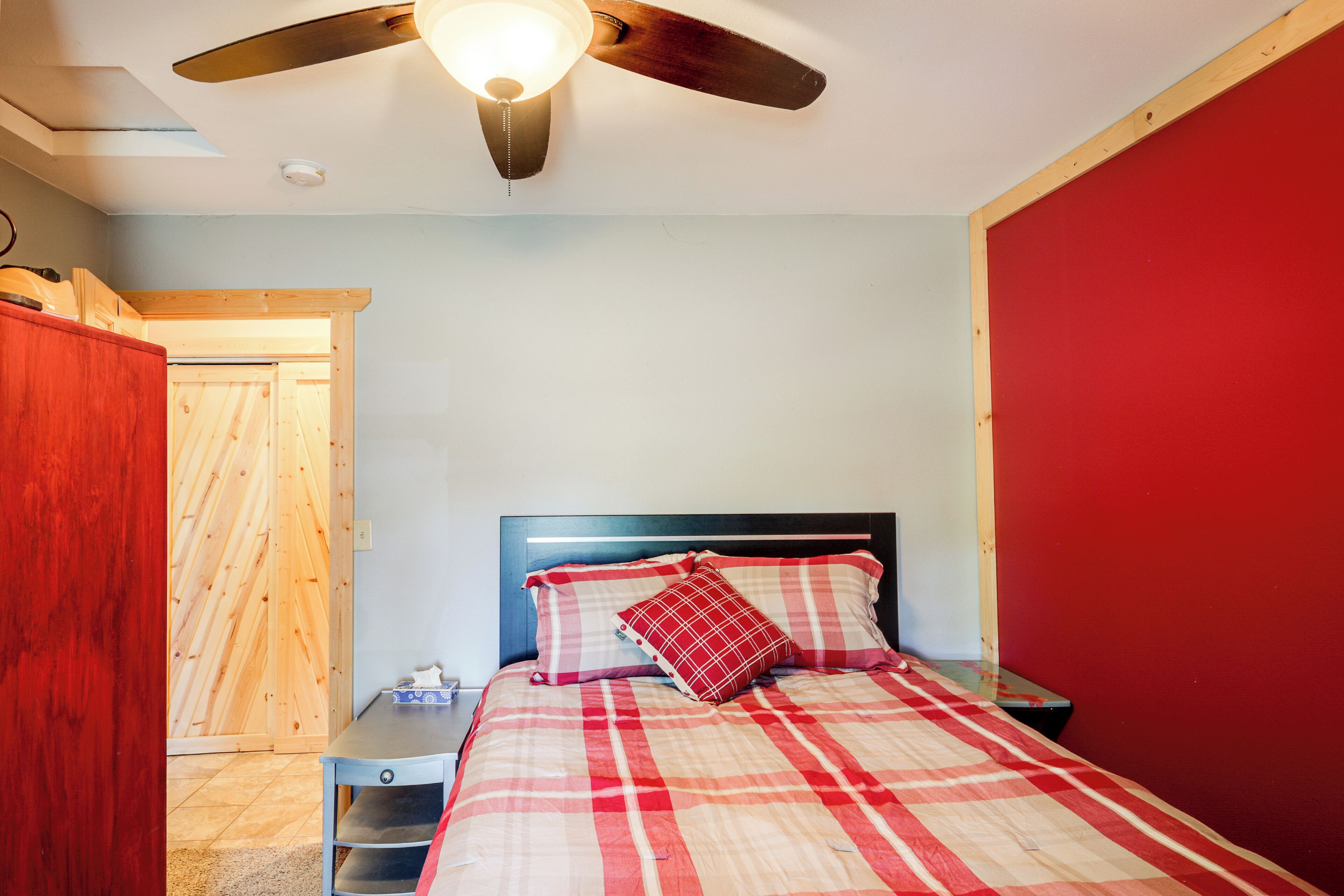 Ein Schlafzimmer mit Bett, Deckenventilator, Nachttisch und Holztür.