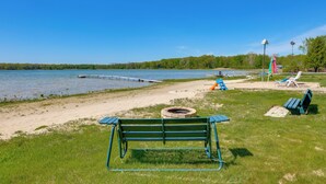Un parc au bord du lac, équipé d’un banc, de tables de pique-nique et d’un foyer.