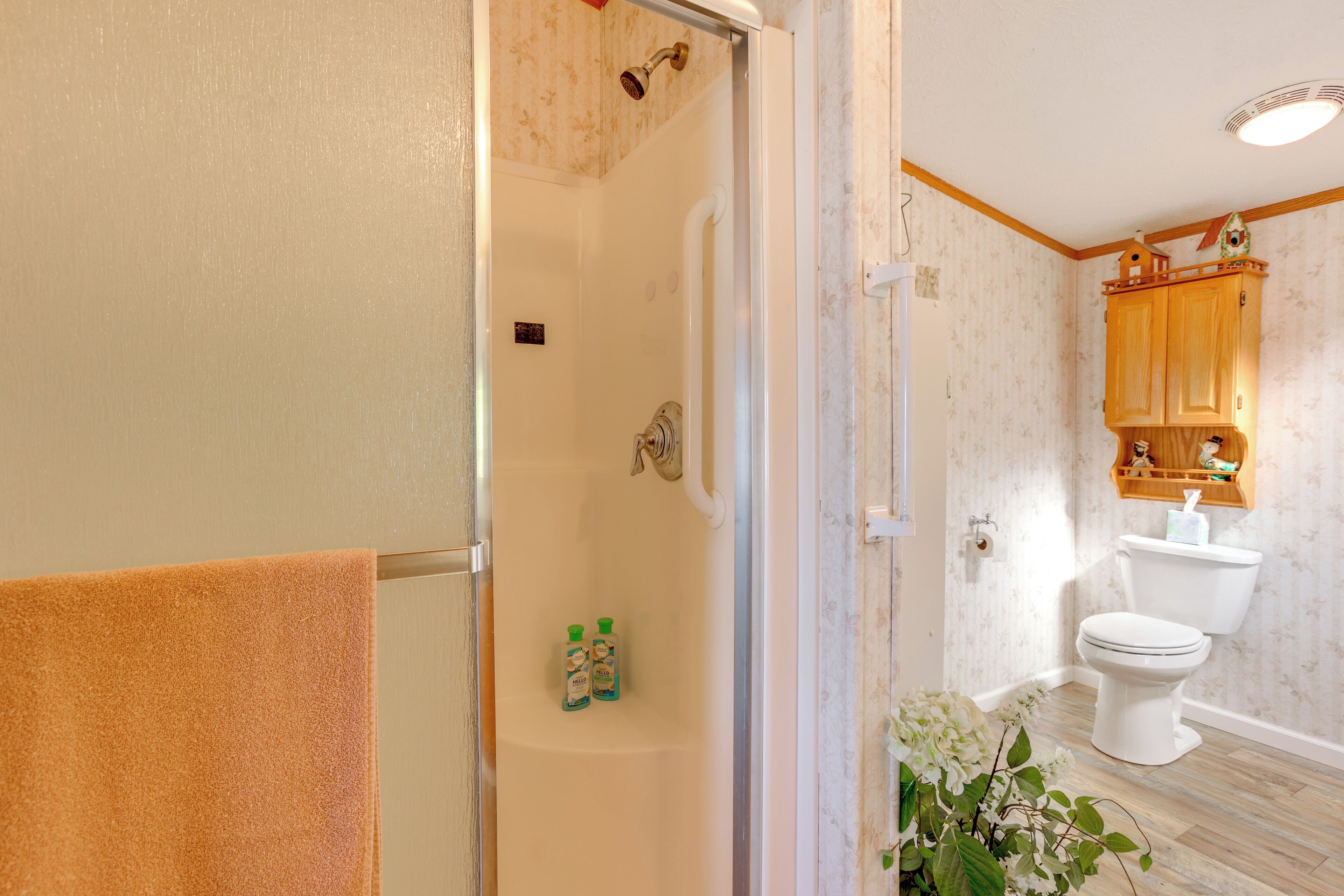 A bathroom with a shower, toilet, and wooden cabinets.
