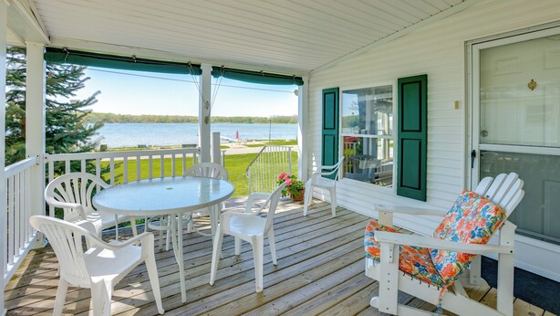 Une terrasse couverte, dotée d’une table et de chaises, qui offre une vue sur un lac.