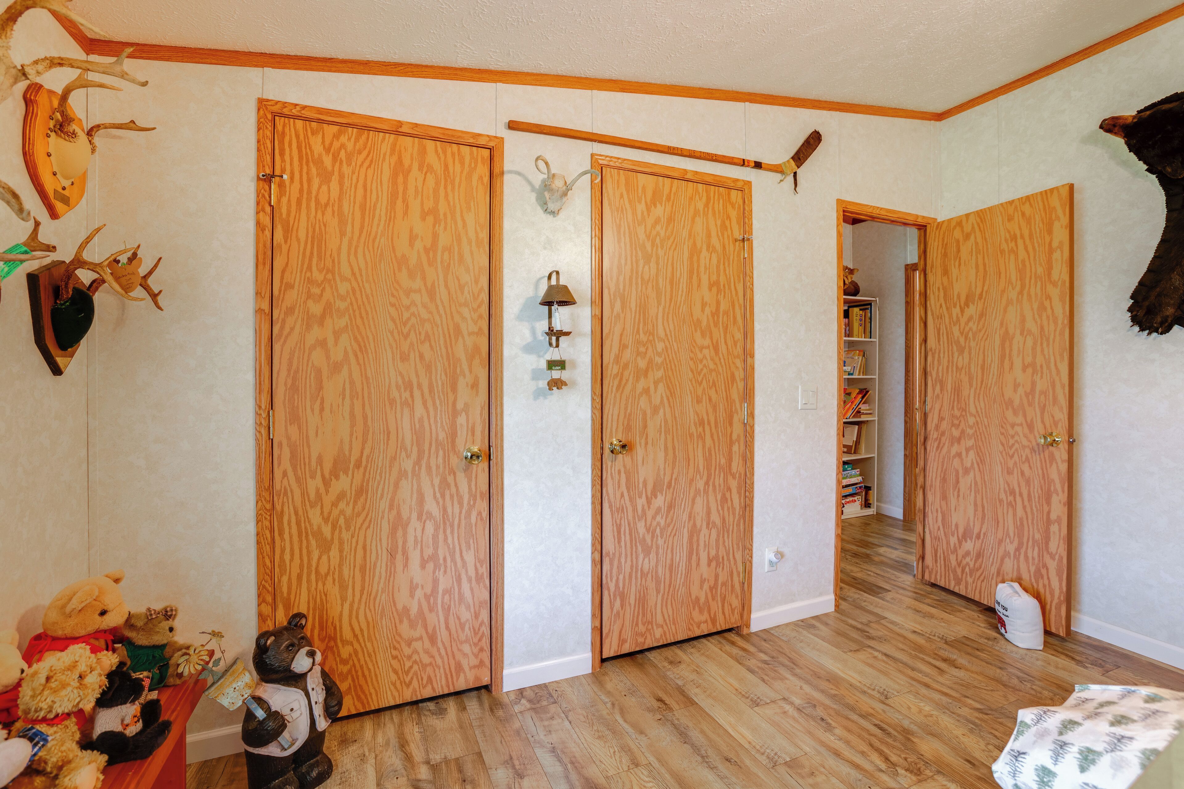 Een kamer met houten vloeren, een houten deur en een plank met pluchen dieren.