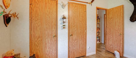 Een kamer met houten vloeren, een houten deur en een plank met pluchen dieren.