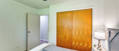 A bedroom with a bed, a wooden wardrobe, a nightstand with a lamp, and a ceiling fan.