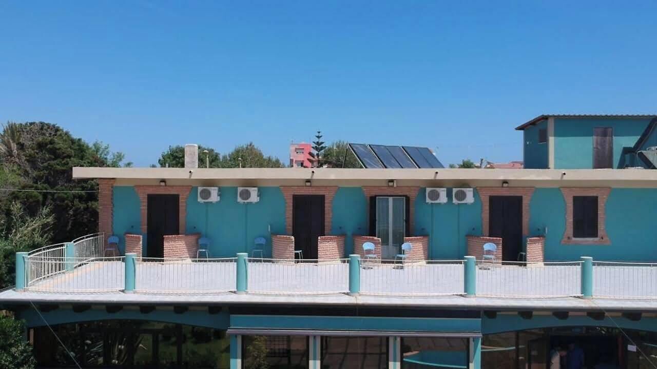 Un edificio de dos pisos con balcón, unidades de aire acondicionado y paneles solares.
