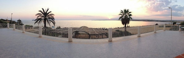 Stroll along the promenade with a clear view of the sea, surrounded by palm trees and a lamp post.